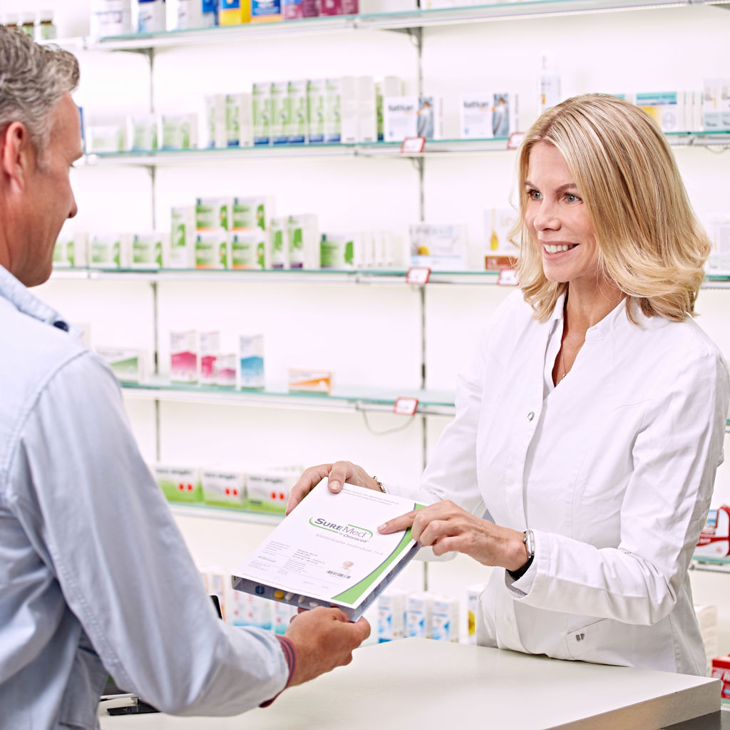 A pharmacist hands a SureMed pack to a customer