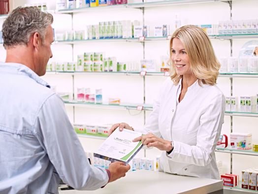 A pharmacist hands a SureMed pack to a customer